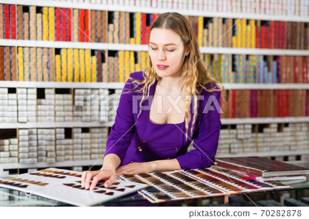 Interested attractive girl looking at palette of hair colors in cosmetics store Interested attractive girl looking at palette of hair colors in cosmetics store 70282878
