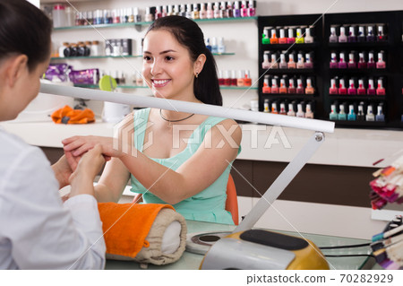 female manicurist filing and shaping nails in beauty salon 70282929
