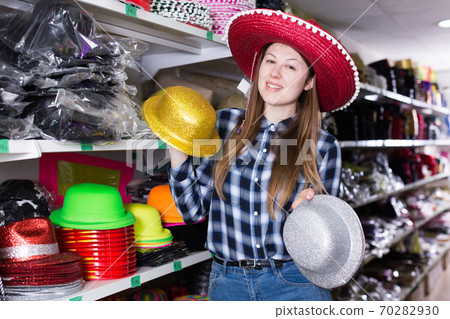 Woman choosing funny headdresses in store 70282930