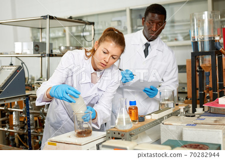 Focused lab technician woman with tubes and worried man technician Focused lab technician woman with tubes and worried man technician 70282944