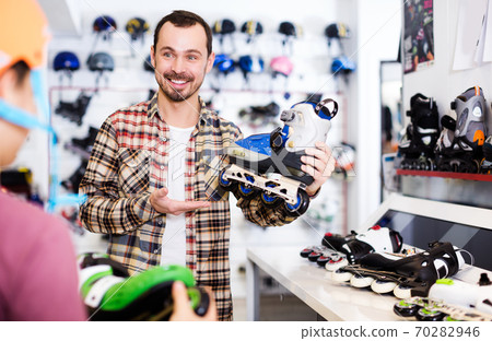 Seller assisting boy in choosing roller-skates Seller assisting boy in choosing roller-skates 70282946