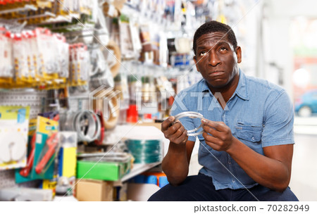 salesman arranging different goods on stand in shop salesman arranging different goods on stand in shop 70282949