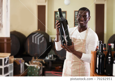afro male seller of wine shop offering wine bottle to buy afro male seller of wine shop offering wine bottle to buy 70282951