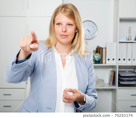 Confident businesswoman pointing to invisible screen Confident businesswoman pointing to invisible screen 70283174