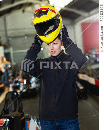 Young woman puts equipment for karting Young woman puts equipment for karting 70283198