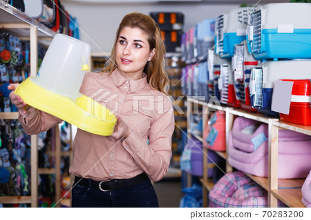 Glad positive woman choosing pet food dispenser Glad positive woman choosing pet food dispenser 70283200