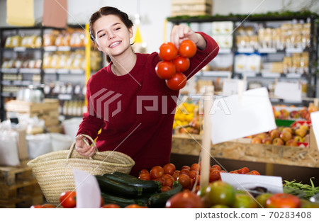 Young girl buying tomatoes at market Young girl buying tomatoes at market 70283408