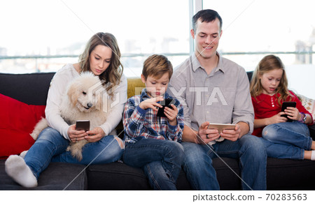 Happy family members spending time playing with smartphones Happy family members spending time playing with smartphones 70283563