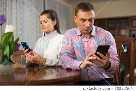 Modern family sitting with smartphones in home interior 70283564