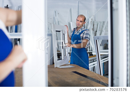 Portrait of male worker with finished plastic window in assembly shop Portrait of male worker with finished plastic window in assembly shop 70283576