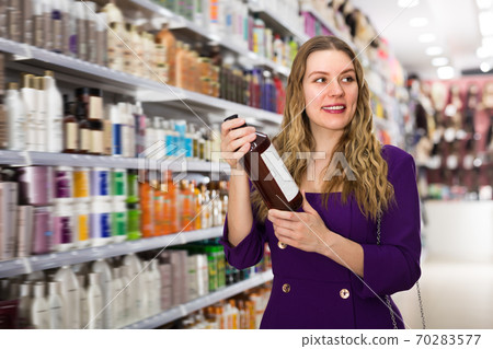 Fine young woman choosing hair care products Fine young woman choosing hair care products 70283577