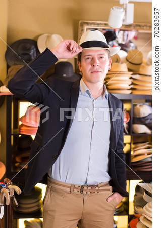 portret of cheerful guy try on panama at headwear store 70283657
