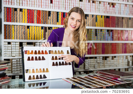 Friendly attractive salesgirl showing palette of hair colors at cosmetics store Friendly attractive salesgirl showing palette of hair colors at cosmetics store 70283691
