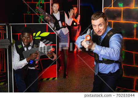 Group of colleagues holding laser pistols playing laser tag game Group of colleagues holding laser pistols playing laser tag game 70283844