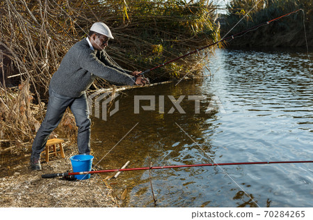 Man standing with fishing rod Man standing with fishing rod 70284265