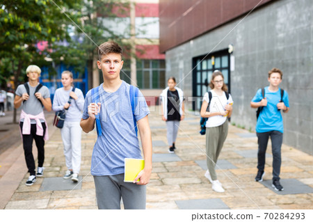Teen boy walking to college campus in autumn day Teen boy walking to college campus in autumn day 70284293