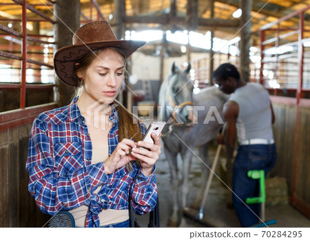 Girl farmer using her smartphone Girl farmer using her smartphone 70284295