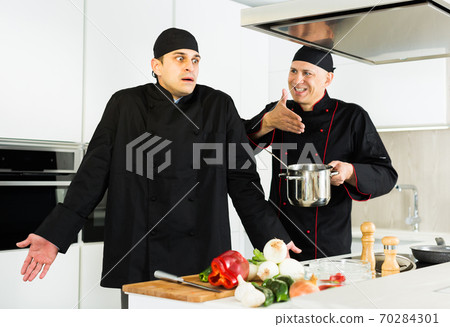 Two male cooks are making salad with emotions on their work place in the kitchen Two male cooks are making salad with emotions on their work place in the kitchen 70284301