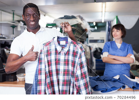Satisfied male client holding clean garment Satisfied male client holding clean garment 70284496