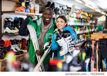 Portrait of cheerful couple posing in full skiing gear during shopping in sport goods store Portrait of cheerful couple posing in full skiing gear during shopping in sport goods store 70284688