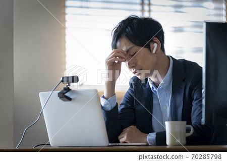 A man holding a head in front of a personal computer 70285798