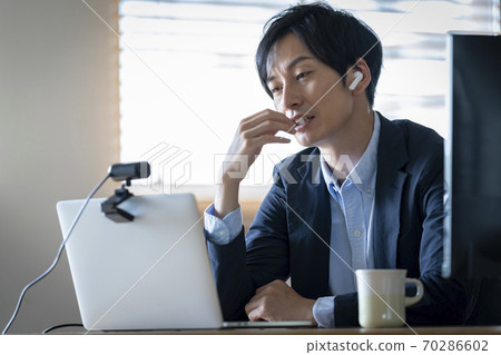 一個男人盯著一台筆記本電腦的屏幕，苦澀的表情 70286602