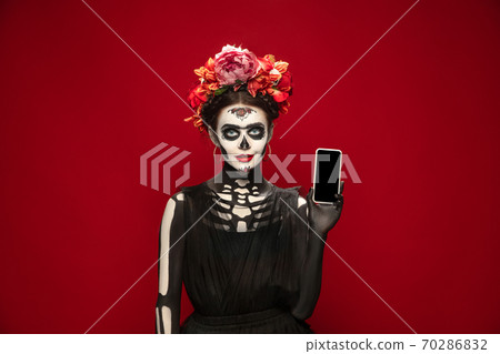 Young girl in the image of Santa Muerte, Saint death or Sugar skull with bright make-up. Portrait isolated on studio background. Young girl in the image of Santa Muerte, Saint death or Sugar skull with bright make-up. Portrait isolated on studio background. 70286832