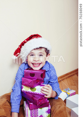 little cute boy with Christmas gifts at home wearing red Santas hat. closeup emotional happy smiling in mess with toys, lifestyle holiday people concept little cute boy with Christmas gifts at home wearing red Santas hat. closeup emotional happy smiling in mess with toys, lifestyle holiday people concept 70288049
