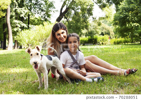 young pretty caucasian mother walking with little cute daughter and dog fox terrier, lifestyle people concept young pretty caucasian mother walking with little cute daughter and dog fox terrier, lifestyle people concept 70288051