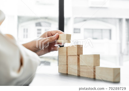 Hands of businesswomen playing wooden block game. Concept Risk of management and strategy plans for business growth and success Hands of businesswomen playing wooden block game. Concept Risk of management and strategy plans for business growth and success 70289729