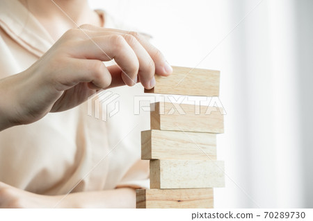 Hands of businesswomen playing wooden block game. Concept Risk of management and strategy plans for business growth and success Hands of businesswomen playing wooden block game. Concept Risk of management and strategy plans for business growth and success 70289730