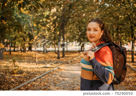 Fall Travel, Autumn trip, getaway, Vacations, solo travel. Plus size girl with backpack in the autumn park 70290050