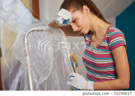 woman holding paint roller for wall painting and empty paint bucket with copy space isolated on  background. Instruments for renovation apartment room. Repair home concept 70290617