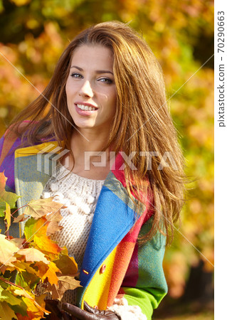 Beautiful elegant woman standing in a park in autumn Beautiful elegant woman standing in a park in autumn 70290663