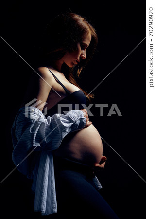 Profile of pregnant woman over black background 70290920
