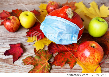 A mask on autumn pumpkin with colorful leaves, healthcare and hygiene concept. A mask on autumn pumpkin with colorful leaves, healthcare and hygiene concept. 70291255