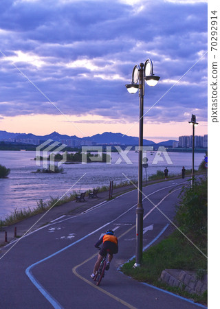 Bike rider man running on the riverside road at dawn 70292914