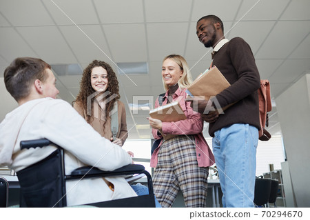 Students Talking to Wheelchair User in College 70294670