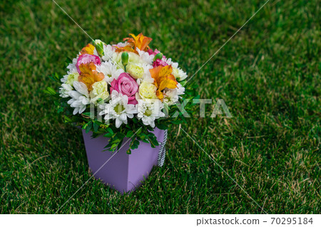 bouquet flowers in hatbox on lawn. place for text. 70295184