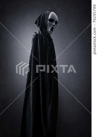 Ghostly figure in hooded cloak in the dark 70295789