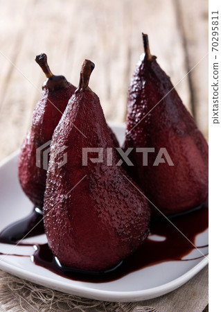 Poached pears in red wine on rustic wooden table Poached pears in red wine on rustic wooden table 70295811
