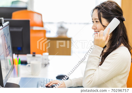 一邊看著電腦屏幕一邊通過電話接到訂單的女人 一邊看著電腦屏幕一邊通過電話接到訂單的女人 70296757