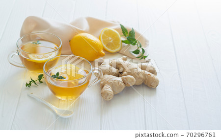 Cups of healthy ginger tea with mint leaves and lemon on white table 70296761