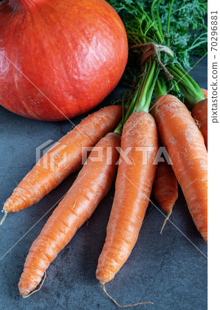 Carrots with fresh leaves and a pumpkin on dark background 70296881