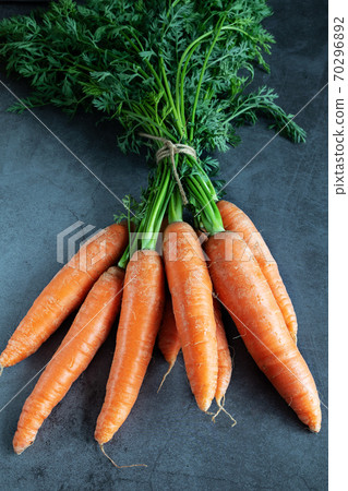 Various carrots with fresh leaves on dark background 70296892