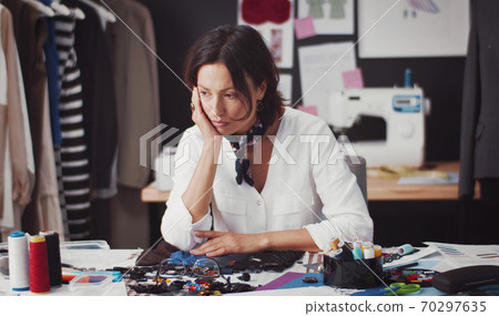 Pensive fashion designer sitting desk Pensive fashion designer sitting desk 70297635