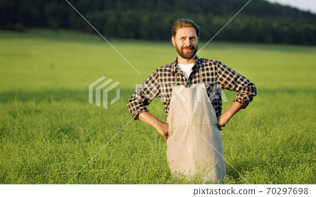 Farmer standing among green field Farmer standing among green field 70297698