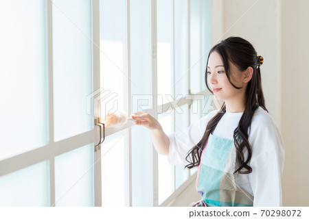 A housewife cleaning the window frame where the sunlight shines 70298072