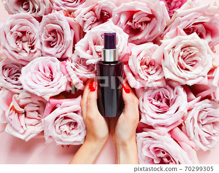 Mockup of dark brown spray bottle, caucasian female hands with red nails and roses on pink table. Top view, copy space Mockup of dark brown spray bottle, caucasian female hands with red nails and roses on pink table. Top view, copy space 70299305