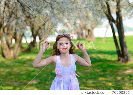 Pretty little girl in blooming apple tree garden on beautiful spring day 70300205